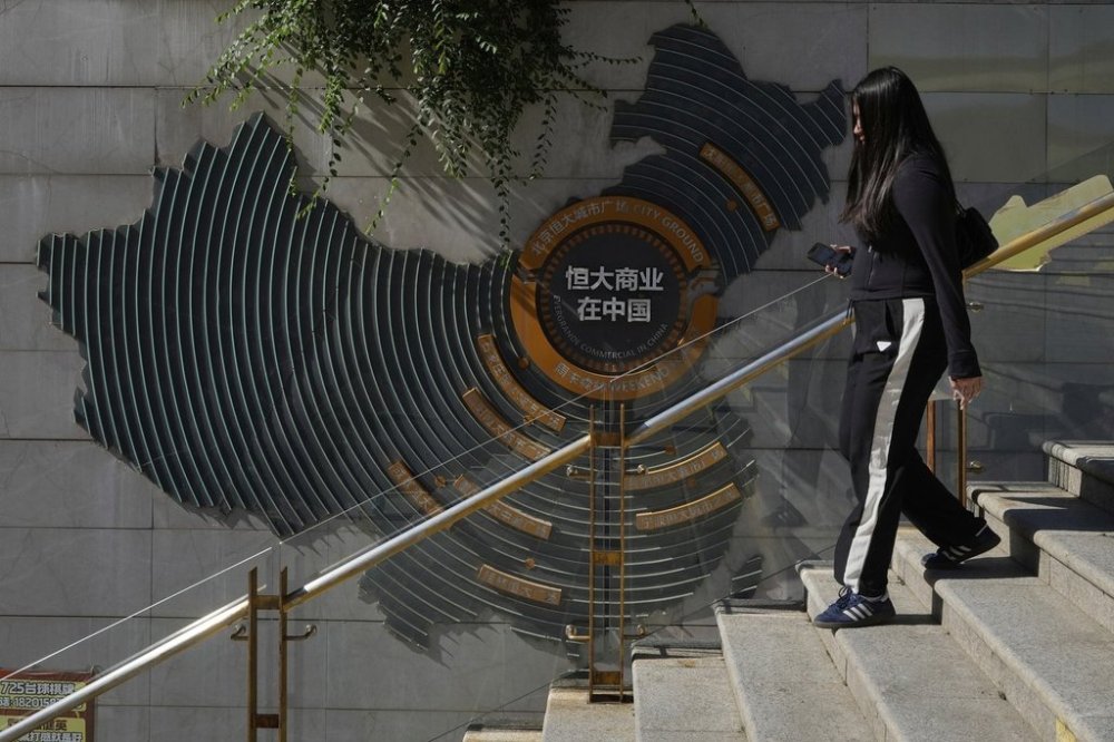 A woman walks past a depiction of Evergrande properties across a China map at a partially shuttered Evergrande commercial complex, in Beijing, China, Monday, Aug. 25, 2025. (AP Photo/Mahesh Kumar A.)