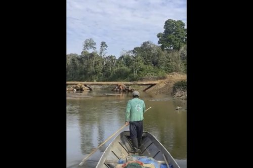 In this frame from video provided by Survival International, Dabi Nishida, of the Yine Indigenous group, maneuvers a boat near a bridge built by the company Maderera Canales Tahuamanu along the Tahuamanu River in the Peruvian Amazon’s Mashco Piro territory near the Nueva Oceania village on Aug. 18, 2025. (Courtesy of Survival International via AP)
