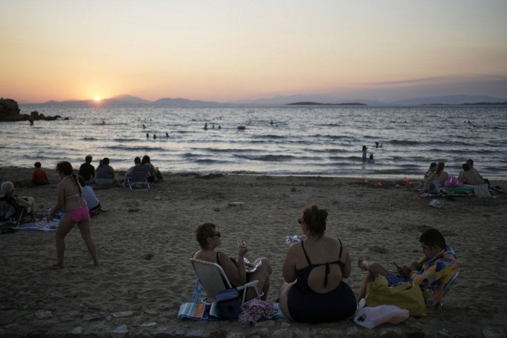 People gather at Kavouri beach as the sun sets in southern Athens, Greece, Monday, Aug. 11, 2025. (AP Photo/Thanassis Stavrakis)