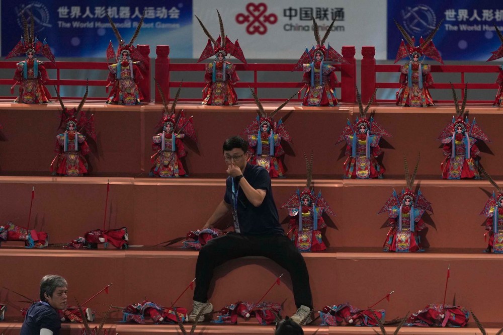 A man prepares robots dressed like Beijing Opera performers ahead of the opening ceremony of the World Humanoid Robot Games held in Beijing, China, Thursday, Aug. 14, 2025. (AP Photo/Ng Han Guan)