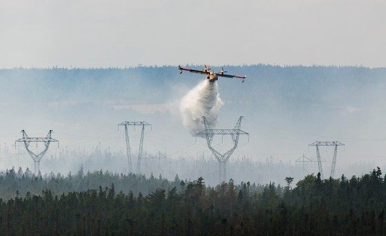 A water bomber provides a steady steam of water to assist crews on the ground at the Paddy's Pond wildfire, just outside St. John's, N.L., on Aug. 14. (Paul Daly / The Canadian Press files)