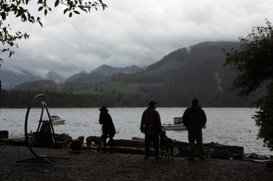 People look from the shoreline of the Alberni Inlet towards Mount Underwood, where a wildfire continues to burn across from Macktush Creek Campsite, south of Port Alberni, B.C., on Aug. 16. (Chad Hipolito / The Canadian Press files)