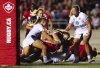 Canada's Olivia DeMerchant (18) scores a try as she is tackled by USA's Erica Jarrell-Searcy (5), bottom, and McKenzie Hawkins (10), left, during the second half of Women's rugby action in Ottawa on Friday, Aug. 1, 2025. THE CANADIAN PRESS/Sean Kilpatrick