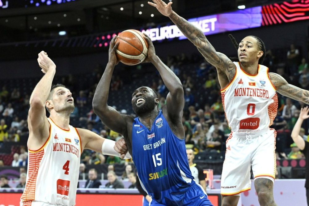 Montenegro's Nikola Vucevic, left, and Kyle Allman Jr., right, challenge for the ball with Britain's Akwasi Yeboah, center, during the Eurobasket, European Basketball Championship, group B match between Montenegro and Great Britain in Tampere, Finland, Wednesday, Sept. 3, 2025. (Heikki Saukkomaa/Lehtikuva via AP)