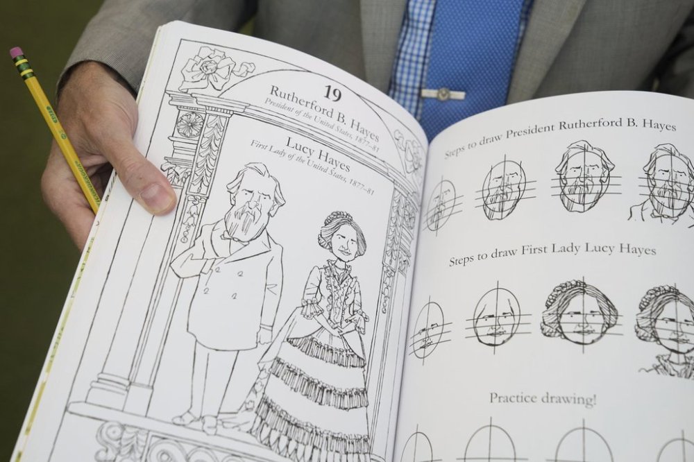 John Hutton, illustrator and professor of art history at Salem College, holds open his book,