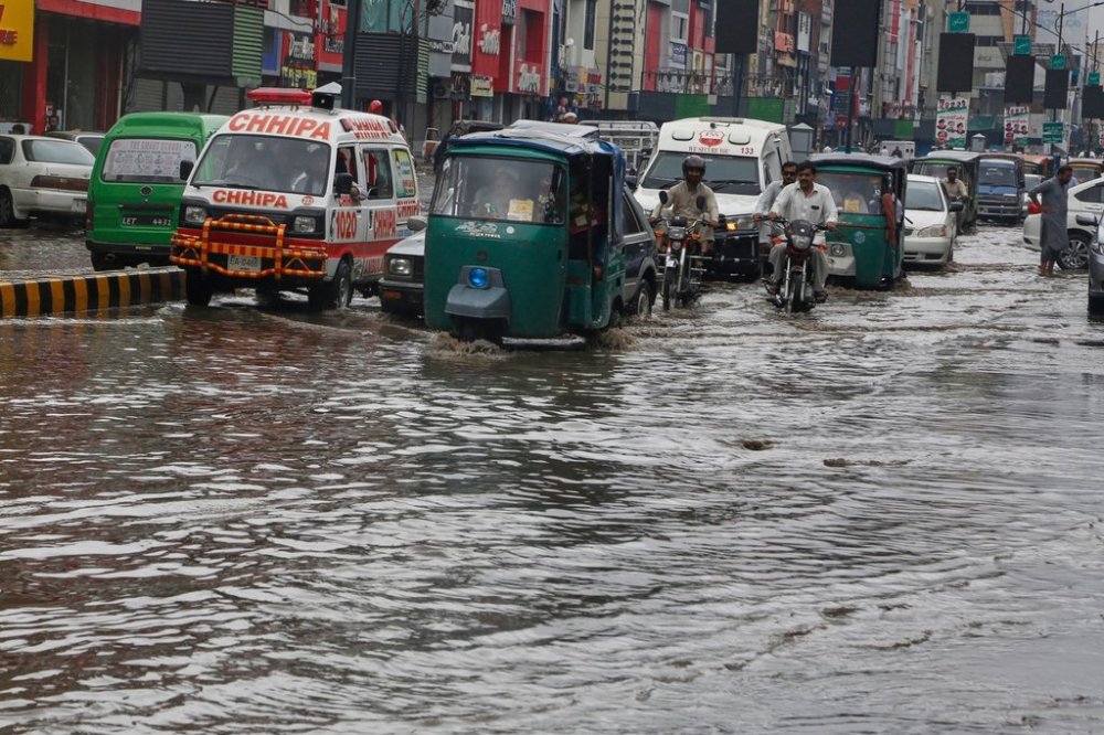 Vehicles and motorcyclists drive through a flooded road after heavy rainfall in Peshawar, Pakistan, Monday, Aug. 18, 2025. (AP Photo/Muhammad Sajjad)