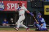 Philadelphia Phillies' Edmundo Sosa, left, follows through on a solo home run swing as Texas Rangers catcher Kyle Higashioka, right, looks on in the fifth inning of a baseball game Sunday, Aug. 10, 2025, in Arlington, Texas. (AP Photo/Tony Gutierrez)