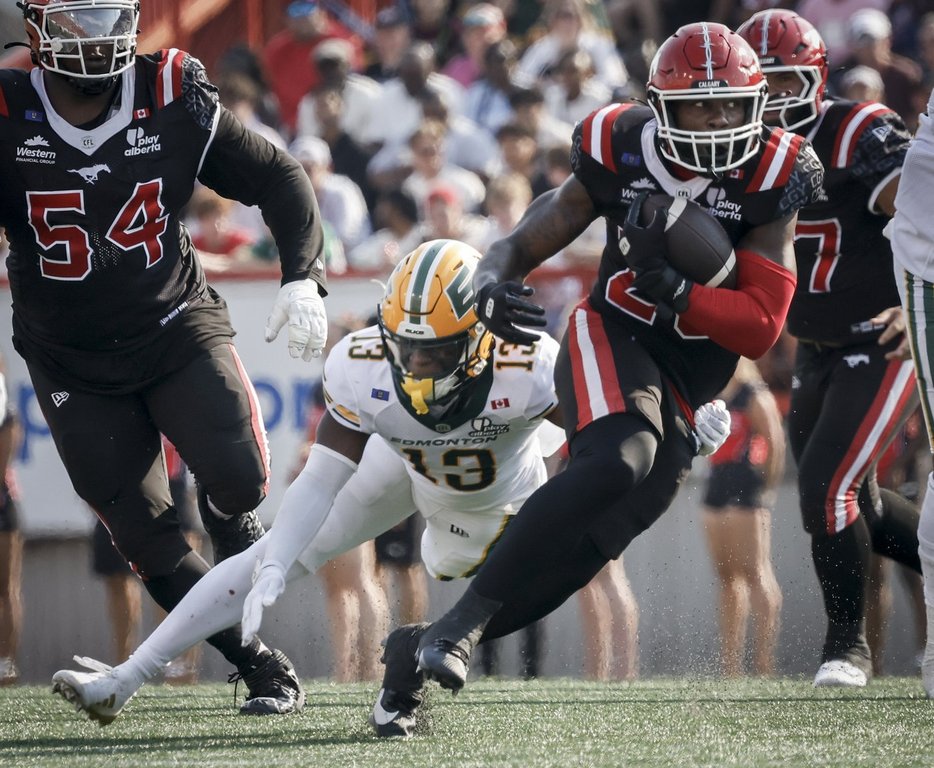 Edmonton Elks' Kordell Jackson, left, grabs for Calgary Stampeders' Dedrick Mills during first half CFL football action in Calgary, Alta., Monday, Sept. 1, 2025. THE CANADIAN PRESS/Jeff McIntosh