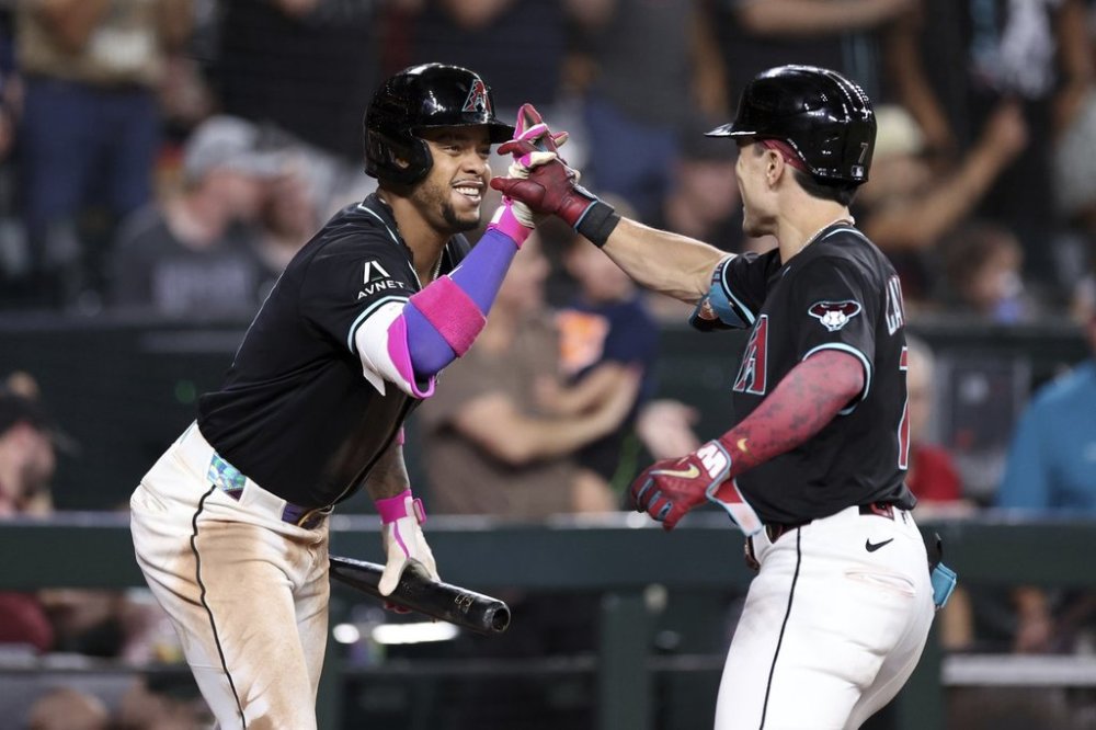 Arizona Diamondbacks' Corbin Carroll, right, high-fives Ketel Marte, left, after hitting a two-run home run against the Colorado Rockies during the fifth inning of a baseball game Saturday, Aug. 9, 2025, in Phoenix. (AP Photo/Chris Coduto)
