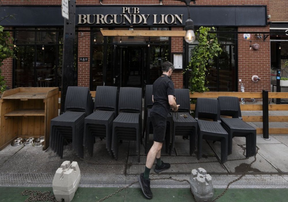 Adam Fazackerley, an employee at Pub Burgundy Lion opens the patio in Montreal, Wednesday, Aug. 13, 2025. THE CANADIAN PRESS/Christinne Muschi