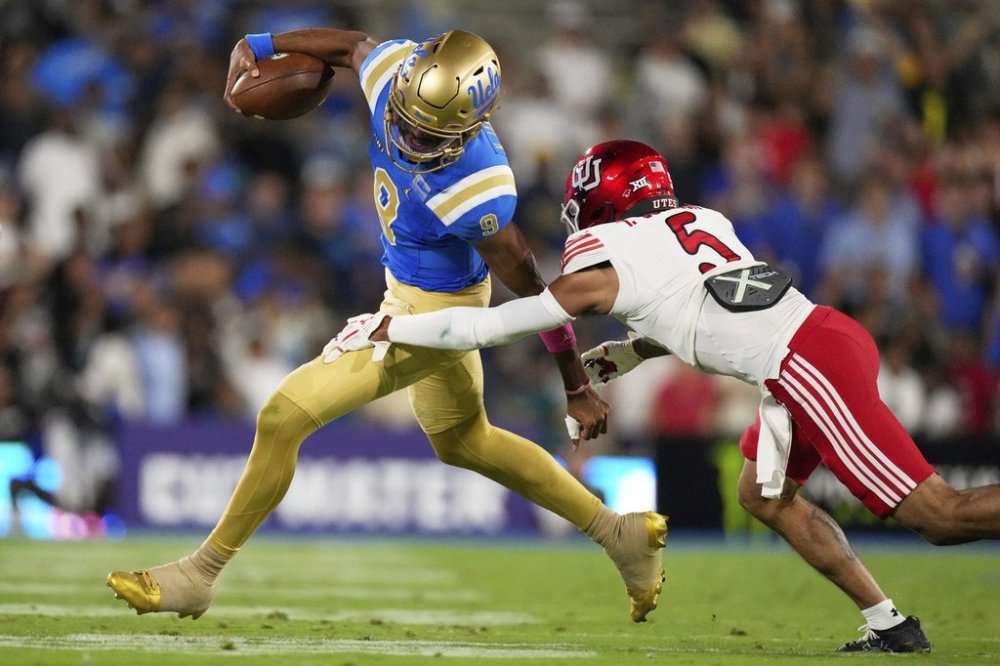 UCLA quarterback Nico Iamaleava, left, avoids a tackle by Utah safety Tao Johnson during the first half of an NCAA college football game, Saturday, Aug. 30, 2025, in Pasadena, Calif. (AP Photo/Mark J. Terrill)