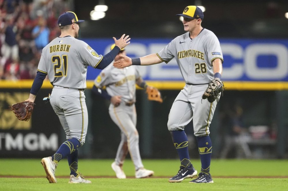 Milwaukee Brewers' Caleb Durbin, left, and Milwaukee Brewers' Andrew Vaughn, right, celebrate their win at the conclusion of the ninth inning of a baseball game against the Cincinnati Reds, Friday, Aug. 15, 2025, in Cincinnati. (AP Photo/Kareem Elgazzar)