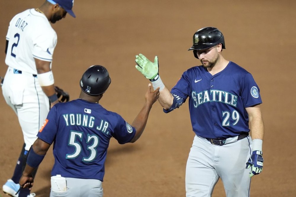 Seattle Mariners' Cal Raleigh (29) celebrates his single off Tampa Bay Rays pitcher Shane Baz with first base coach Eric Young Jr. (53) during the sixth inning of a baseball game Monday, Sept. 1, 2025, in Tampa, Fla. (AP Photo/Chris O'Meara)