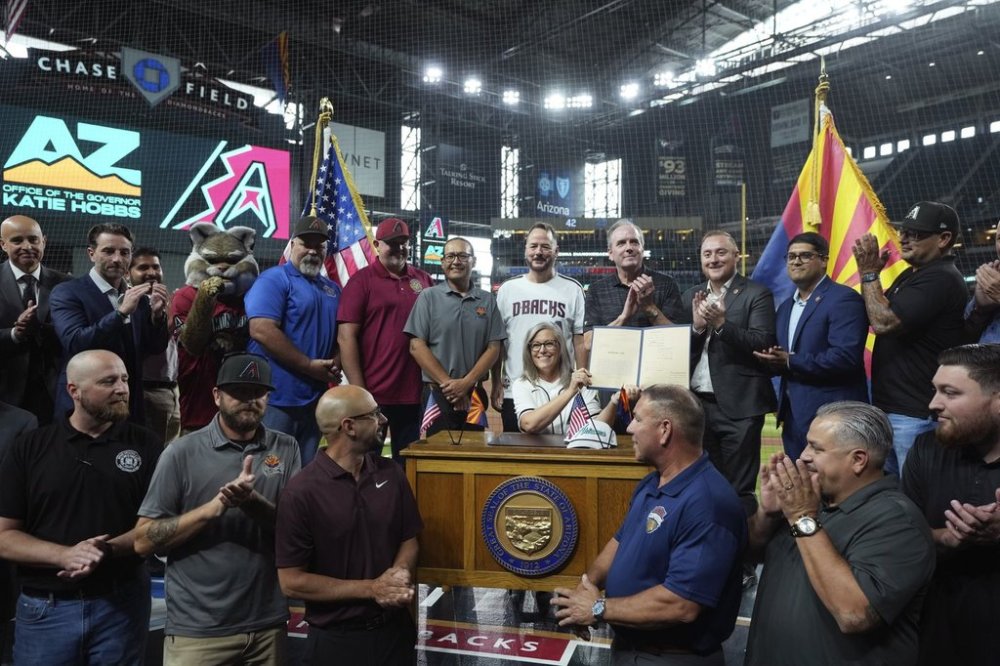 Arizona Democratic Gov. Katie Hobbs, right, is joined by Arizona Diamondbacks staff, and local politicians and union members during a ceremonial bill signing of HB2704 for Chase Field stadium funding prior to a baseball game between the Arizona Diamondbacks and the Texas Rangers Wednesday, Sept. 3, 2025, in Phoenix. (AP Photo/Ross D. Franklin)