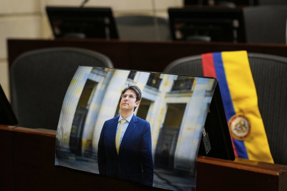 A photo of opposition Sen. Miguel Uribe is placed at his seat in Congress in Bogota, Colombia, Monday, Aug. 11, 2025, after his death more than two months after being shot during a political rally. (AP Photo/Fernando Vergara)