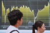 People walk in front of an electronic stock board showing Japan's Nikkei index at a securities firm Friday, Aug. 1, 2025, in Tokyo. (AP Photo/Eugene Hoshiko)