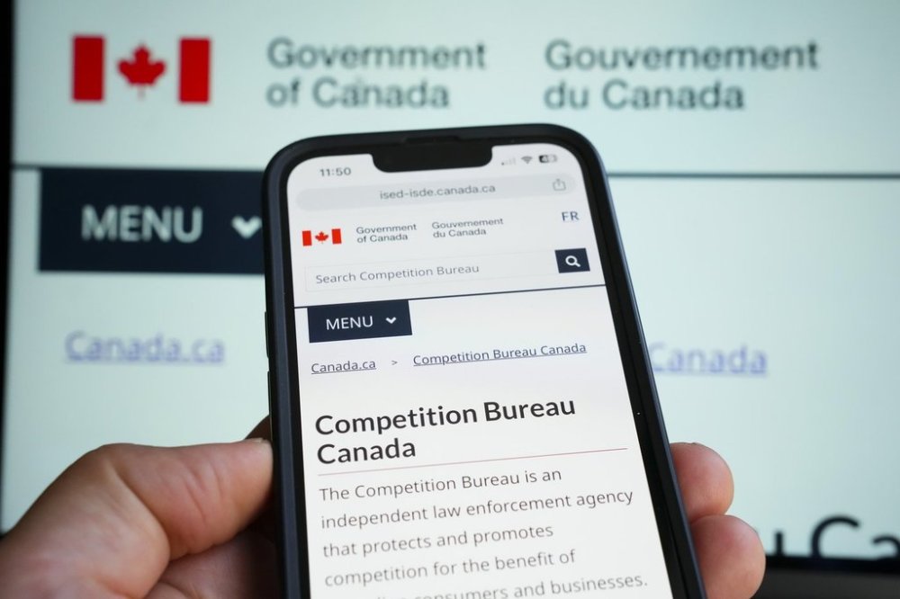 The Canadian Government's Competition Bureau website is pictures on a mobile phone and laptop screen in Ottawa on Monday, Oct. 2, 2023. THE CANADIAN PRESS/Sean Kilpatrick