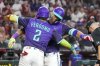 Arizona Diamondbacks' Geraldo Perdomo (2) gives Lourdes Gurriel Jr., right, a hug after Gurriel Jr. hit a home run against the Cincinnati Reds during the third inning of a baseball game Saturday, Aug. 23, 2025, in Phoenix. (AP Photo/Darryl Webb)