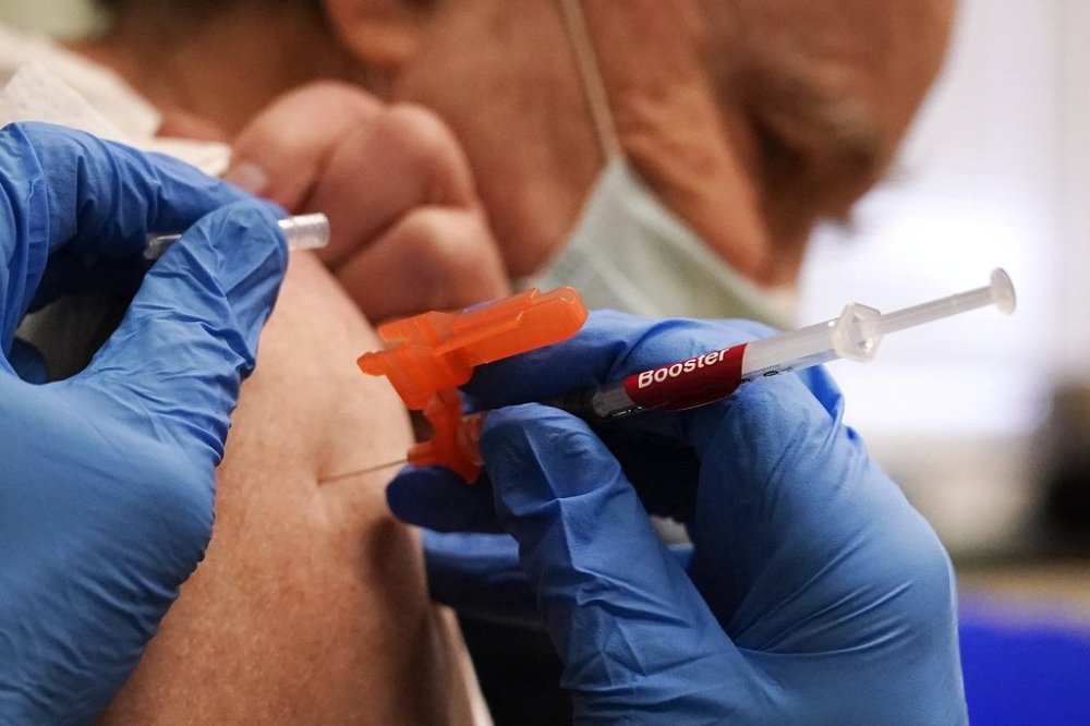 FILE - Pharmacist Kenni Clark injects Robert Champion, of Lawrence, Mass., with a booster dosage of the Moderna COVID-19 vaccine during a vaccination clinic at City of Lawrence's