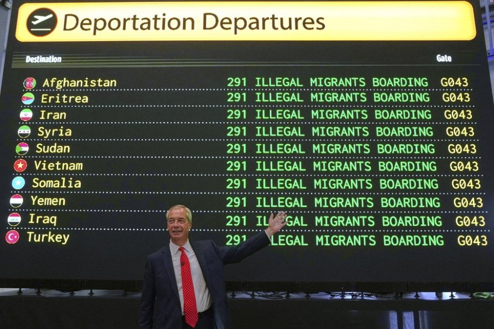 British Reform party leader Nigel Farage poses in front of a mock departures board during a press conference in a hangar at Oxford Airport in Kidlington, England, Tuesday, Aug. 26, 2025.(AP Photo/Joanna Chan)