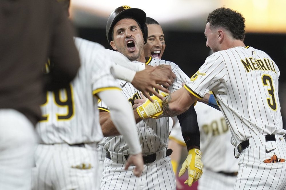 San Diego Padres' Ramon Laureano, center, is swarmed by teammates after hitting a walk-off RBI single during the tenth inning of a baseball game Saturday, Aug. 9, 2025, in San Diego. The Padres won 5-4. (AP Photo/Gregory Bull)