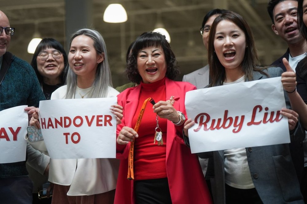 Billionaire Ruby Liu, centre, poses with her staff while holding a set of keys to a former Hudson's Bay-owned Saks Off 5th department store during a