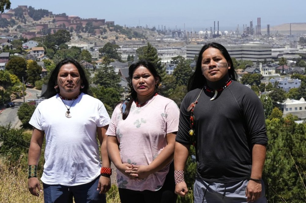 FILE - Juan Bay, president of the Waorani people of Ecuador, from left, Jhajayra Machoa Mendúa and Nadino Calapucha, a spokesperson for the Kichwa Pakkiru people, pose for a photograph as a Chevron refinery is visible in the background, June 19, 2025, in Richmond, Calif. (AP Photo/Godofredo A. Vásquez, File)