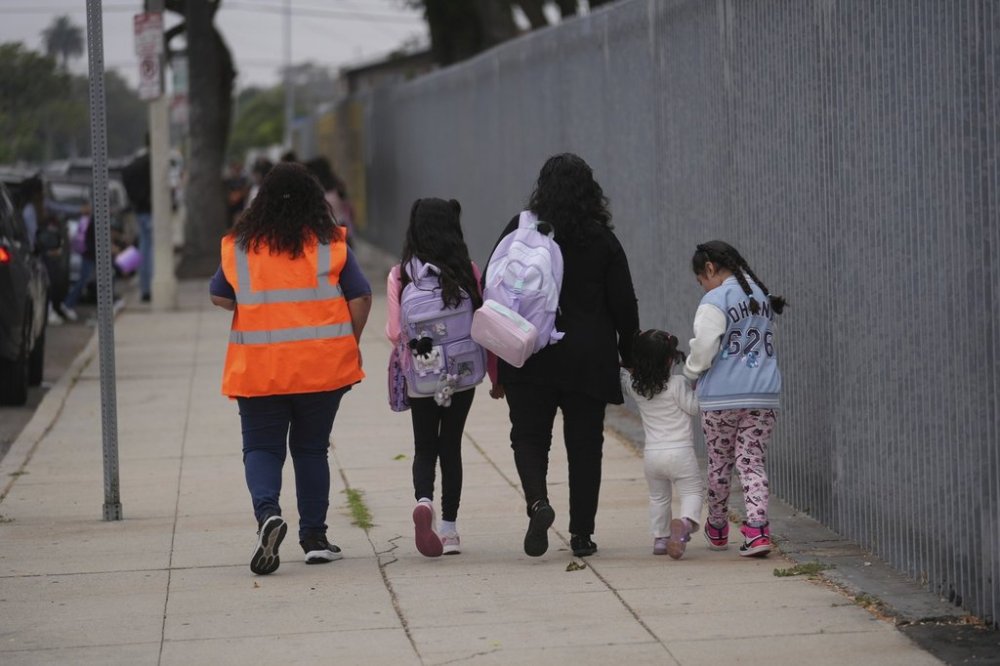 FILE - Students and family members are escorted into school on the first day of school Thursday, Aug. 14, 2025, in Los Angeles. (AP Photo/Marcio Jose Sanchez, File)