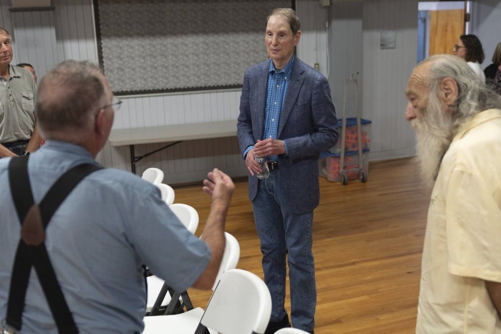 Sen. Ron Wyden, D-Ore., center, speaks to T.L. Fassbender, left, after a town hall meeting on Friday, July 25, 2025, in Wasco, Ore. (AP Photo/Jenny Kane)