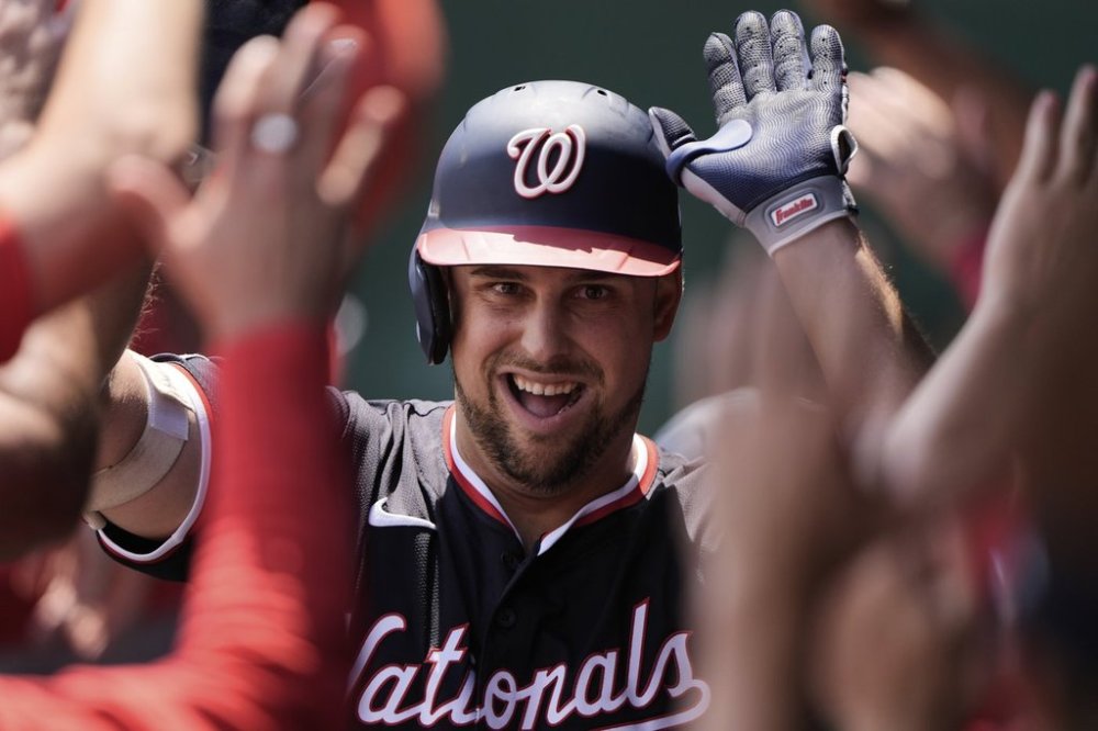 Washington Nationals' Nathaniel Lowe celebrates in the dugout after hitting a grand slam during the first inning of a baseball game against the Kansas City Royals, Wednesday, Aug. 13, 2025, in Kansas City, Mo. (AP Photo/Charlie Riedel)