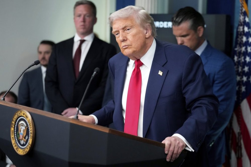 President Donald Trump, in foreground, listens to a question from a reporter as White House Deputy Chief of Staff Taylor Budowich, from left, Army Secretary Dan Driscoll and Defense Secretary Pete Hegseth look on in the James Brady Press Briefing Room at the White House, Monday, Aug. 11, 2025, in Washington. (AP Photo/Mark Schiefelbein)