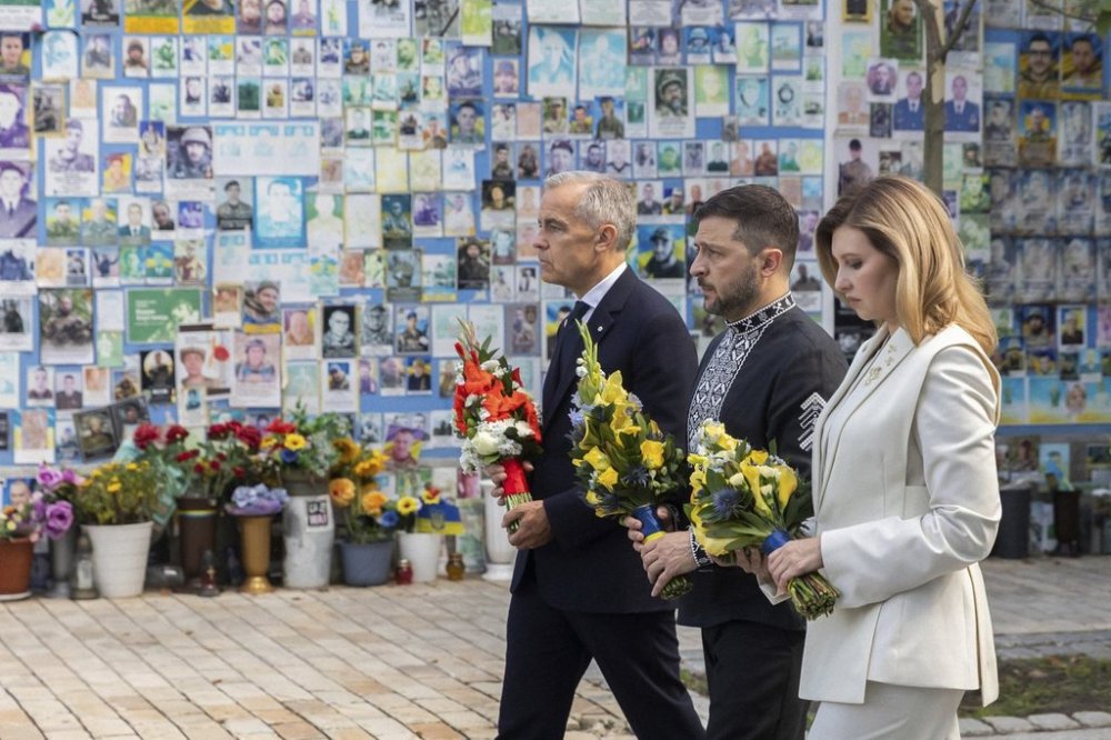 In this photo provided by the Ukrainian Presidential Press Office, Prime Minister Mark Carney, left, Ukrainian President Volodymyr Zelenskyy, center, and his wife Olena attend a flower laying ceremony at the Memory Wall of Fallen Defenders of Ukraine in Kyiv, Ukraine, on Sunday, Aug. 24, 2025. (Ukrainian Presidential Press Office via AP)