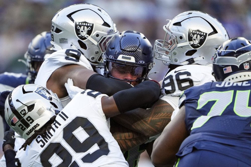 Seattle Seahawks running back George Holani (36) is tackled by Las Vegas Raiders defensive end Tyree Wilson (9), safety Chris Smith II (29) and tight end Albert Okwuegbunam (86) during the first half of an NFL preseason football game Thursday, Aug. 7, 2025, in Seattle. (AP Photo/Lindsey Wasson)