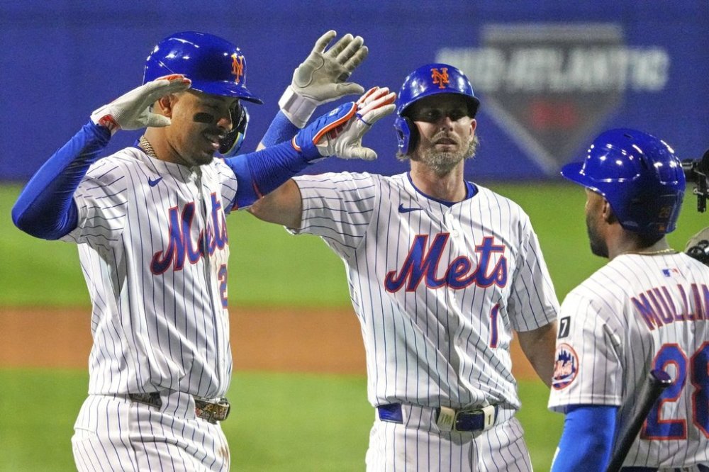 New York Mets third base Mark Vientos, left, is greeted by Jeff McNeil (1), and Cedric Mullins (28) as he returns to the dugout after hitting a three-run home run off Seattle Mariners pitcher George Kirby during the fifth inning of the Little League Classic baseball game at Bowman Field in Williamsport, Pa., Sunday, Aug. 17, 2025. (AP Photo/Gene J. Puskar)
