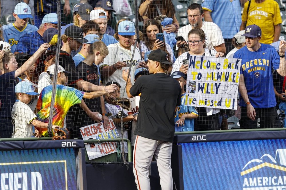 San Francisco Giants shortstop Willy Adames gives autographs before a baseball game against the Milwaukee Brewers, Friday, Aug. 22, 2025, in Milwaukee. (AP Photo/Jeffrey Phelps)