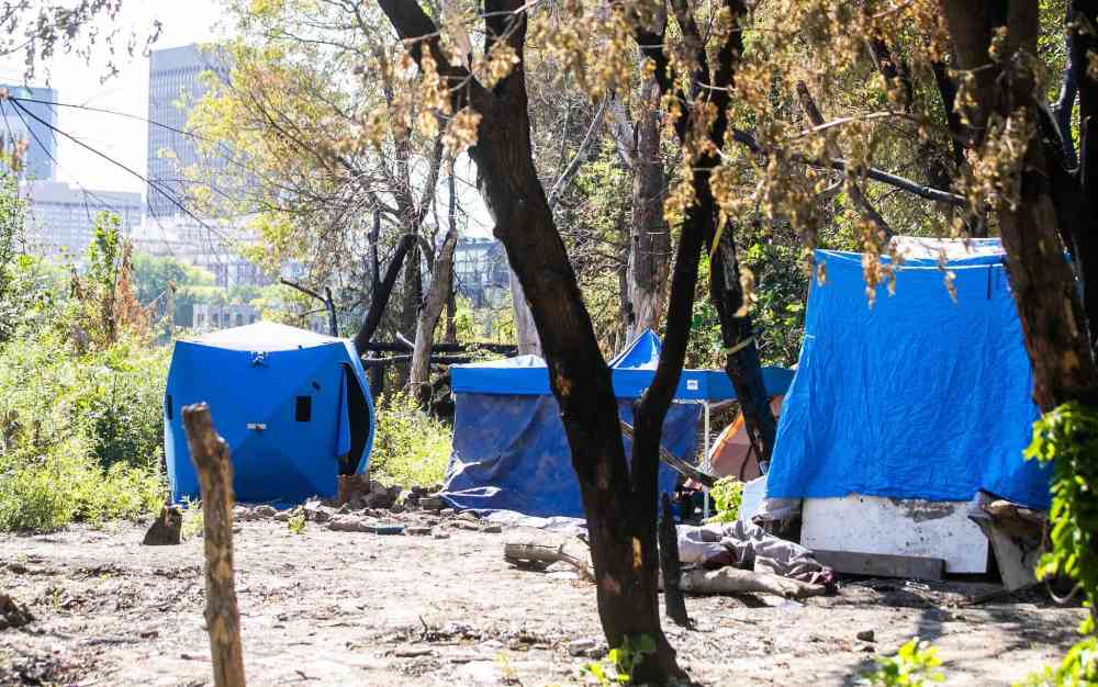 MIKAELA MACKENZIE / FREE PRESS
Winnipeg Police officers collected more than a dozen bikes, stacks of rubber and assorted bike parts from inside the riverbank structure that was draped in tarps.