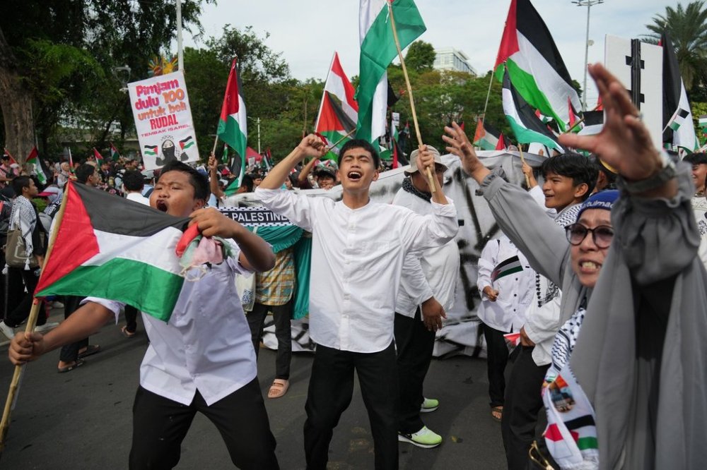 Protesters wave Palestinian flags as they shout slogans during a rally commemorating the second anniversary of the war in Gaza, outside the US Embassy in Jakarta, Indonesia, Tuesday, Oct. 7, 2025. (AP Photo/Achmad Ibrahim)