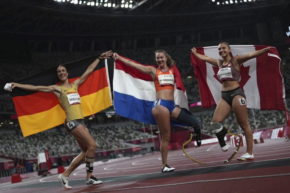 Netherland's Marlene van Gansewinkel, centre, celebrates with Irmgard Bensusan of Germany, second place, and Canada's Marissa Papaconstantinou, third place, after winning the women's T64 100m final at Tokyo 2020 Paralympic Games, Friday, Sept. 3, 2021, in Tokyo, Japan. (AP Photo/Emilio Morenatti)