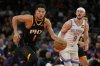FILE - Phoenix Suns guard Devin Booker (1) drives past Oklahoma City Thunder guard Alex Caruso (9) during the second half of an NBA basketball game, April 9, 2025, in Phoenix. (AP Photo/Rick Scuteri, File)