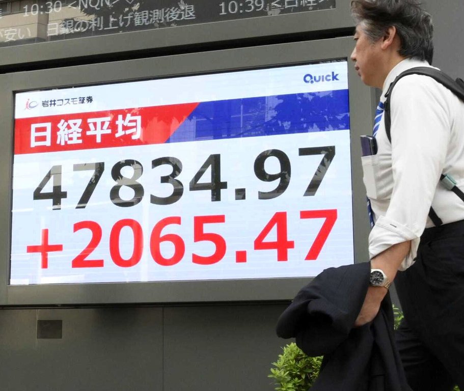 People walks by an electronic stock board showing Japan's Nikkei 225 index at a securities firm in Tokyo, Monday, Oct. 6, 2025. (Kyodo News via AP)