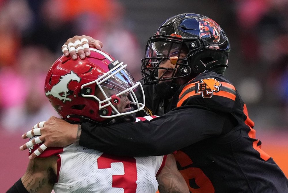Calgary Stampeders quarterback Vernon Adams Jr., left, is hit by B.C. Lions' Bradlee Anae after releasing the ball during the first half of a CFL football game, in Vancouver, on Saturday, Oct. 4, 2025. THE CANADIAN PRESS/Darryl Dyck