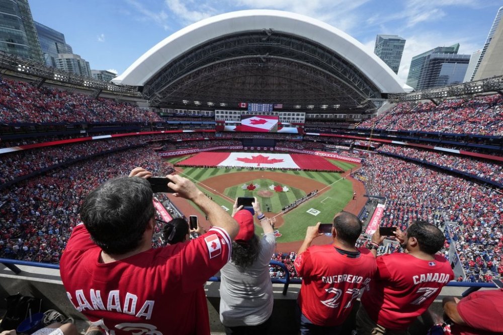 Fans take photos as a large Canadian flag is unfurled before the start of the MLB game between New York Yankees and the Toronto Blue Jays in Toronto on Canada Day, Tuesday, July 1, 2025. THE CANADIAN PRESS/Frank Gunn