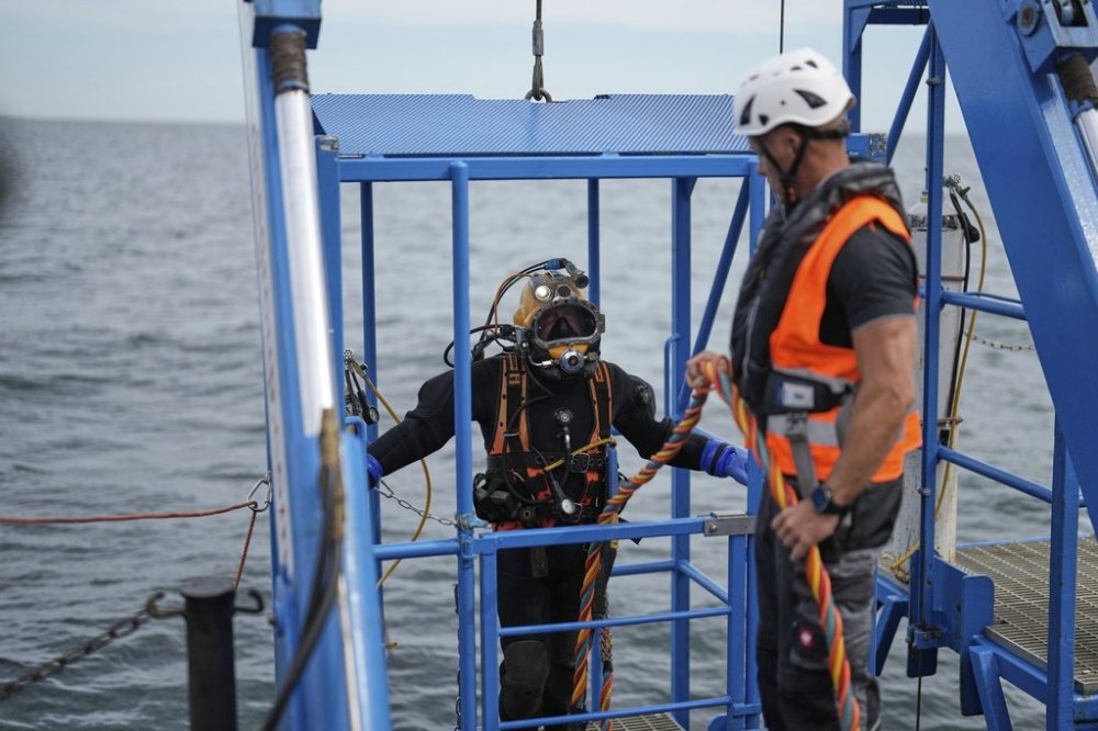 A diver is lowered into the water during a press tour to show the recovering of ammunition from World War II in the Baltic Sea near Boltenhagen, Germany, Monday, Sept. 1, 2025. (AP Photo/Markus Schreiber)