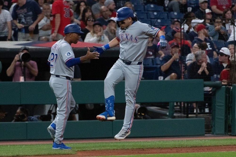 Texas Rangers' Alejandro Osuna, left reacts with third base coach Tony Beasley after hitting a three-run home run off Cleveland Guardians starting pitcher Slade Cecconi during the first inning of a baseball game, Friday, Sept. 26, 2025, in Cleveland. (AP Photo/Phil Long)