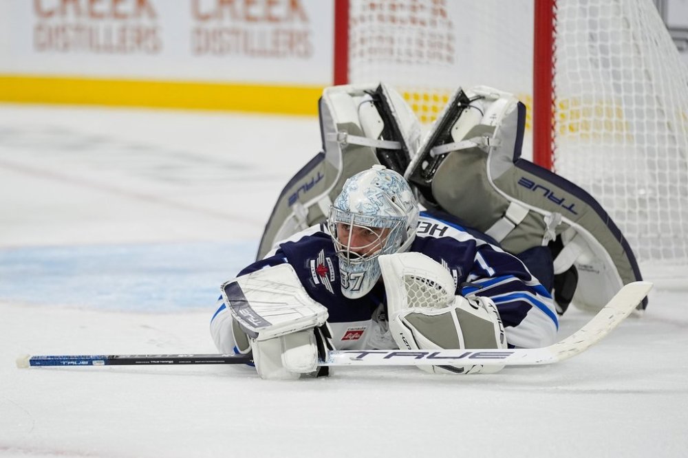 Winnipeg Jets goaltender Connor Hellebuyck (37) lays on the ground after stopping a shot during the third period of an NHL hockey pre-season game against the Minnesota Wild, Tuesday, Sept. 30, 2025, in St. Paul, Minn. (AP Photo/Abbie Parr)