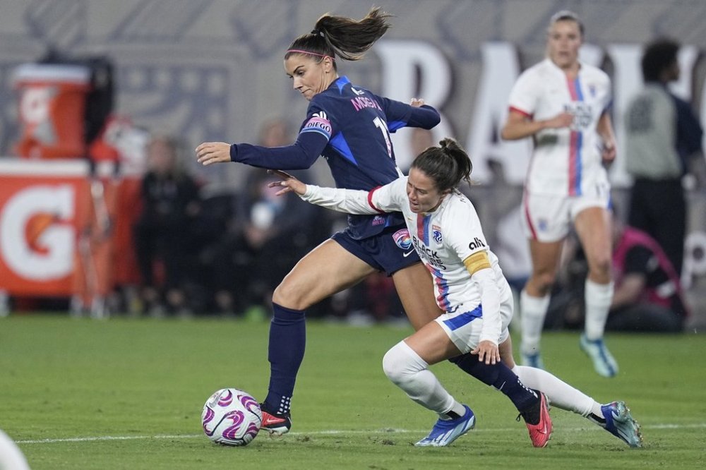 FILE - San Diego Wave forward Alex Morgan, left, controls the ball as OL Reign defender Lauren Barnes defends during the second half of an NWSL semifinal playoff soccer match Sunday, Nov. 5, 2023, in San Diego. (AP Photo/Gregory Bull, File)