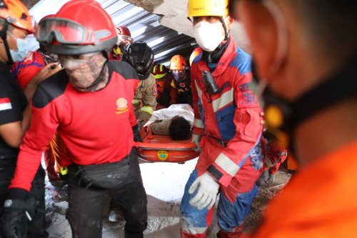Rescuers carry a survivor who was pulled out from the rubble after a building under construction collapsed at an Islamic boarding school in Sidoarjo, East Java, Indonesia, Wednesday, Oct. 1, 2025. (AP Photo/Alam Syahirul)