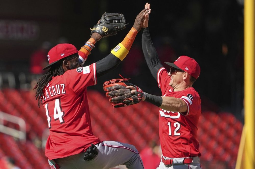 Cincinnati Reds' Austin Hays (12) and Elly De La Cruz (44) celebrate a victory over the St. Louis Cardinals following a baseball game against the St. Louis Cardinals Wednesday, Sept. 17, 2025, in St. Louis. (AP Photo/Jeff Roberson)