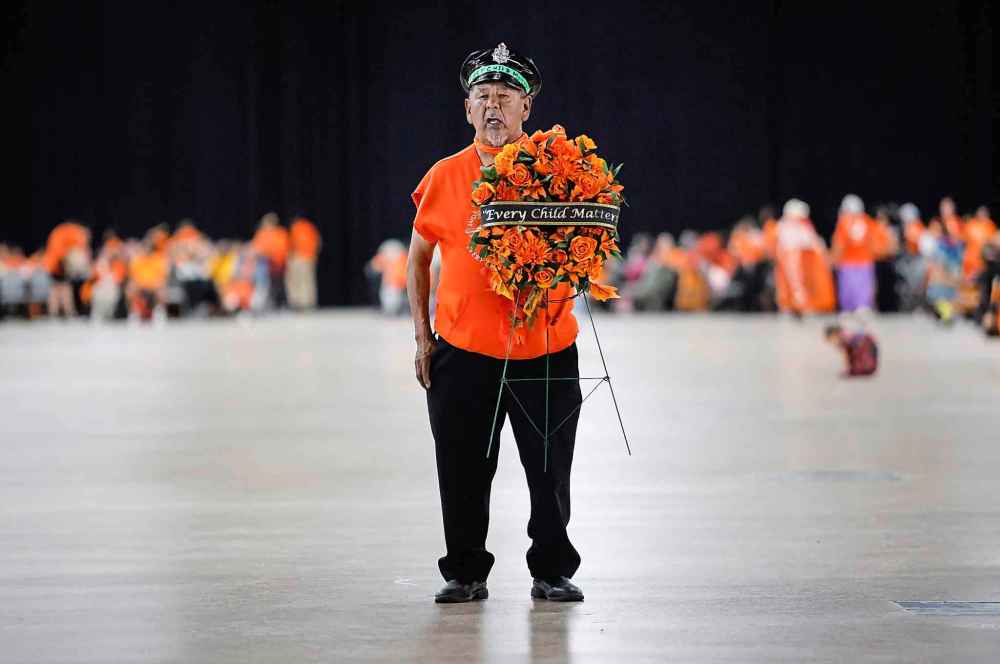 Lawrence Douglas Corbiere carried a wreath from The Forks and stands alone for children on a powwow floor at the RBC Convention Centre as people take part in the Orange Shirt Healing Walk and Powwow in Winnipeg Tuesday,