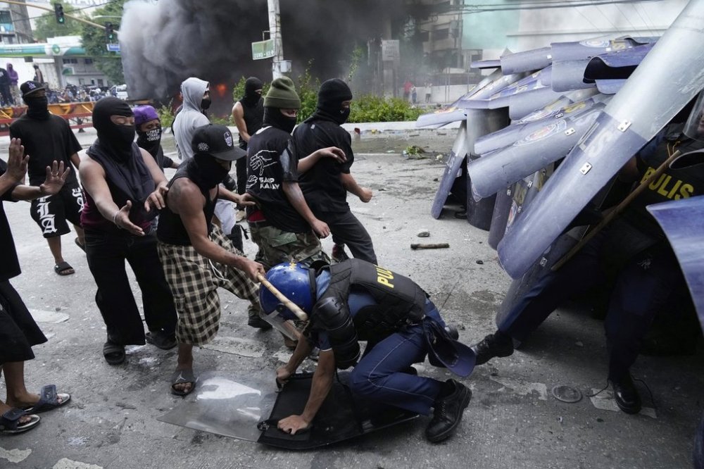 A protester hits police during a scuffle as they tried to enter the Malacanang palace compound in Manila, Philippines on Sunday, Sept. 21, 2025. (AP Photo/Aaron Favila)